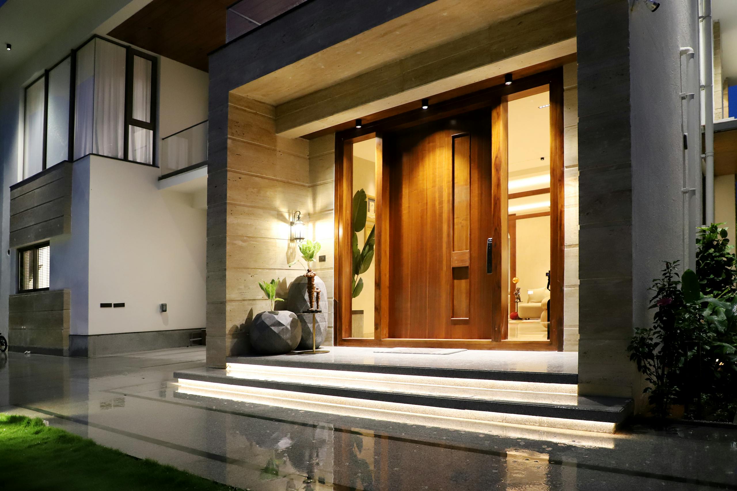 Elegant entrance of a modern house with warm lighting at night, showcasing contemporary architecture.